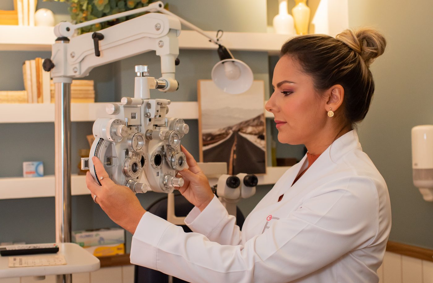 Dra. Isabel Brasil ajustando o refrator no consultório, durante a consulta oftalmológica